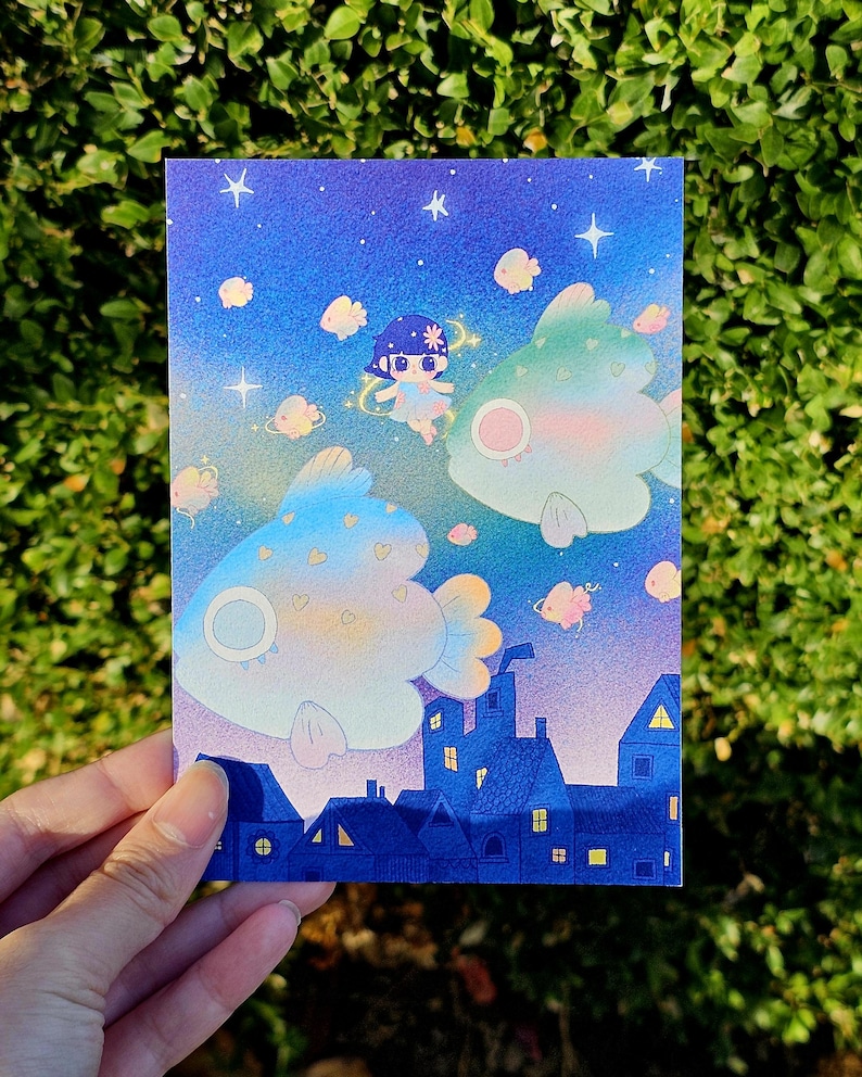 May include: A whimsical illustration featuring a night sky with stars and floating fish. A small figure with a flower crown floats near the fish. Below, a row of blue houses with lit windows adds a touch of fantasy.