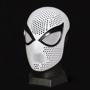 May include: White superhero mask with black eye surrounds and a perforated design. The eye openings have a mesh material. The mask is displayed on a black stand against a black background.