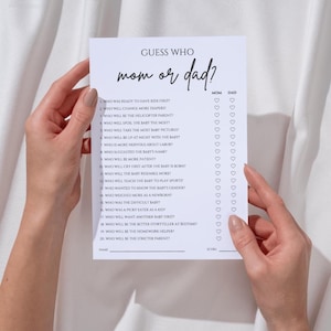 K&ouml;nnte beinhalten: Ein wei&szlig;es Papier-Spielblatt mit dem Text "Guess Who mom or dad?" wird von zwei H&auml;nden gehalten. Das Spielblatt enth&auml;lt eine Liste von Fragen und Felder zum Ankreuzen von Mama oder Papa. Das Spiel ist f&uuml;r eine Babyparty.