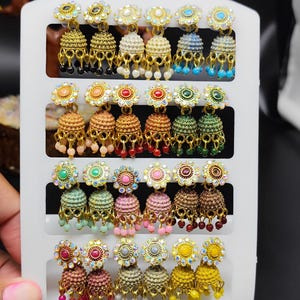 Może przedstawiać: Zestaw trzech ceramicznych kubków z nakrapianym, matowym wykończeniem. Kubki są w odcieniach kremu, jasnoszarym i ciemnoszarym. Każdy kubek ma prosty, minimalistyczny design i zaokrąglony uchwyt.