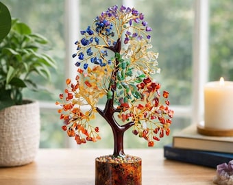 May include: A decorative tree sculpture with a brown trunk and branches made of gold-colored wire. The tree's leaves are colorful gemstones in shades of red, orange, yellow, green, blue, and purple. The tree sits on a brown, cylindrical base.