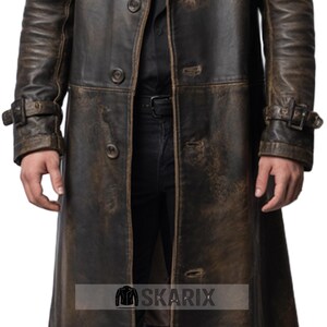 May include: A distressed brown leather trench coat with a button-up front and buckle details on the sleeves. The coat has a vintage, worn appearance. The Skarix logo is visible at the bottom.