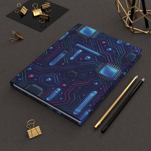 Könnte beinhalten: Ein Notizbuch mit einem Leiterplatten-Design in Blau, Türkis und Rosa. Das Notizbuch wird von goldenen und schwarzen Bleistiften, goldenen Büroklammern und einer geometrischen Goldskulptur umgeben.