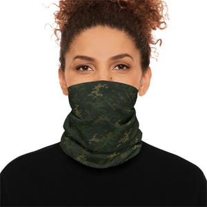 May include: A green and brown camouflage pattern neck gaiter. The neck gaiter is made of a soft, stretchy fabric and is designed to be worn around the neck and face. The camouflage pattern is a pixelated design.