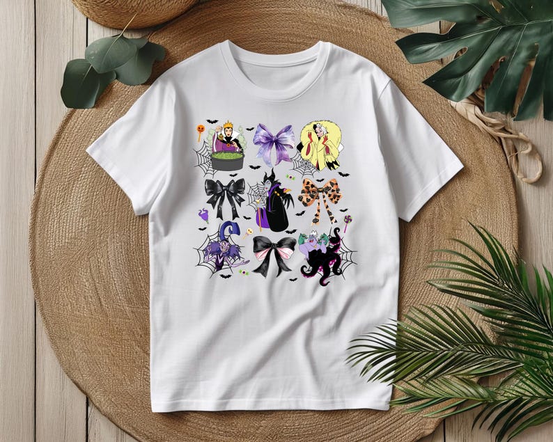 K&ouml;nnte beinhalten: Wei&szlig;es T-Shirt mit einem Halloween-Motiv mit bunten Schleifen. Die Schleifen zeigen verschiedene Charaktere und Elemente, darunter eine Hexe, eine K&ouml;nigin und einen Oktopus. Das Design enth&auml;lt Spinnennetze, Flederm&auml;use und andere gruselige Details.