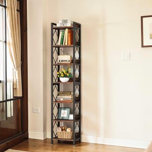 May include: A tall, narrow bookshelf with six shelves. The shelves are made of wood and the frame is black metal. The shelves are filled with books, a radio, flowers, a picture frame, and a basket.