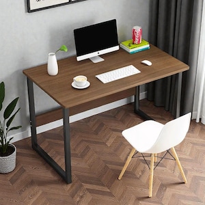 May include: A brown desk with black metal legs, a white chair, and a computer monitor. A white keyboard, mouse, and a cup of coffee are on the desk. A small white vase and a can of Coca-Cola are also visible.