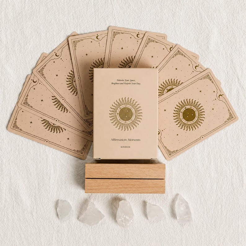 May include: A set of affirmation cards with a sun design, a wooden card holder, and several clear quartz crystals. The card box reads "Affirmation Moments" and "Celebrate Your Space, Brighten and Enliven Your Day."