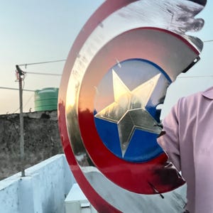 Peut inclure: Un bouclier Captain America avec une finition m&eacute;tallique. Le bouclier pr&eacute;sente un cercle bleu avec une &eacute;toile dor&eacute;e au centre, entour&eacute; de rayures rouges et blanches. Le bouclier a une apparence us&eacute;e et ab&icirc;m&eacute;e.