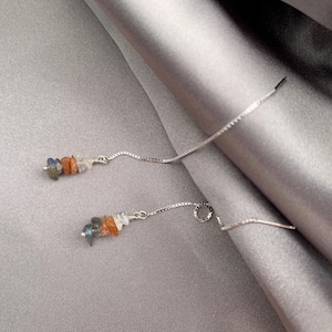 May include: A pair of silver-toned threader earrings featuring a delicate box chain design. Each earring is accented with a cluster of small, irregular, multi-colored gemstone chips in shades of blue, orange, and white, secured by thin wire.