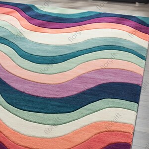 May include: A colorful area rug with a wavy pattern. The rug features stripes of various colors, including red, orange, pink, purple, blue, green, and cream. The rug is made of a soft material and is suitable for a living room or bedroom.