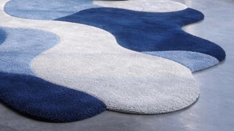 May include: A modern area rug with a flowing, organic design. The rug features a pattern of swirling shapes in shades of blue and white, creating a soft, textured surface. The rug's design adds a contemporary touch to any room.