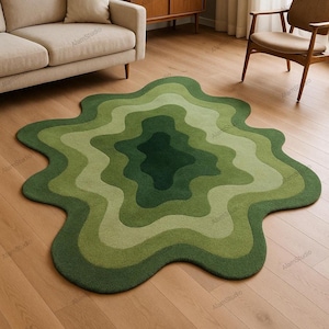 Könnte beinhalten: Ein grüner Teppich mit wellenförmigen Kanten und einem geschichteten Design. Der Teppich weist Grüntöne auf, die einen Farbverlauf erzeugen. Der Teppich liegt auf einem Holzboden und verleiht der Inneneinrichtung einen Hauch von Natur.