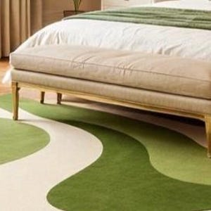 May include: A bedroom scene featuring a green and white patterned rug. The rug's design has a flowing, organic shape. A bed with white linens and a green throw is in the background, along with a bench and a chair.