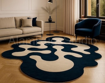 Pode incluir: Um tapete moderno e abstrato com um formato único. O tapete apresenta um fundo azul marinho escuro com um design creme em forma de ameba. O tapete está colocado sobre um piso de madeira em uma sala de estar.