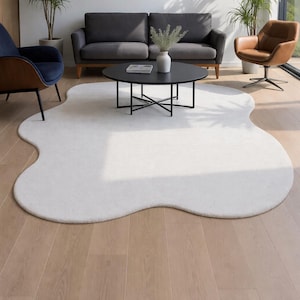 Puede incluir: Una alfombra grande, de color blanco roto, con forma orgánica. La alfombra está colocada sobre un suelo de madera, con una mesa de centro negra y asientos visibles en el fondo. La forma única de la alfombra añade un toque moderno al espacio vital. Medidas: aprox. 200 cm x 300 cm.