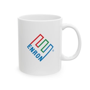 Op de afbeelding: Witte keramische mok met een gebogen handvat. De mok heeft een kleurrijk logo met het woord "ENRON" in blauw, rood en groen. Het logo is een gestileerd ontwerp. De mok heeft een standaard formaat.