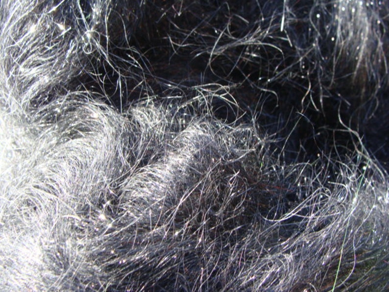 Puede incluir: Primer plano de una tela gris oscura texturizada con un aspecto peludo, casi lanudo. La tela tiene un ligero brillo y parece estar hecha de fibras finas.