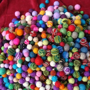 May include: A large pile of colorful felt balls in various patterns and colors, including red, blue, green, yellow, purple, and white.