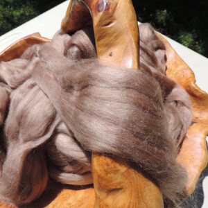 May include: A brown, fluffy fiber in a wooden bowl. The fiber is soft and appears to be natural.