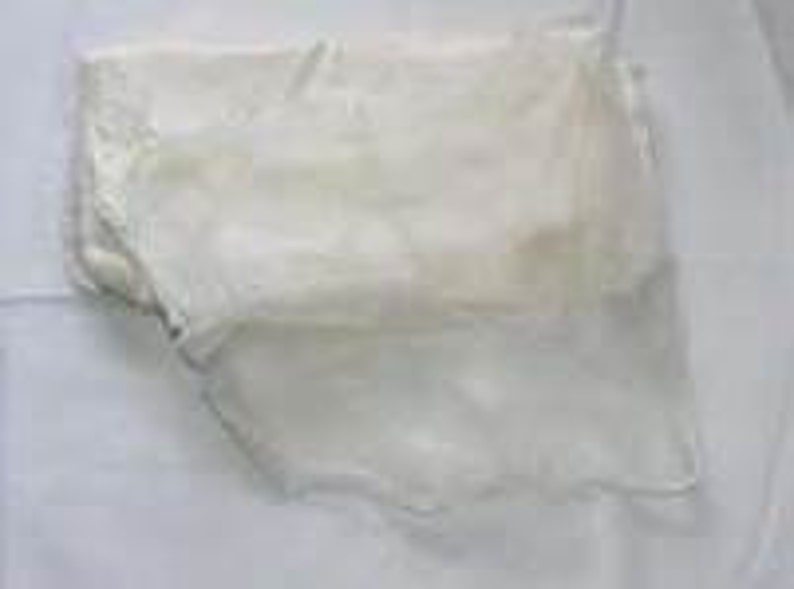 May include: A folded piece of sheer white fabric with a delicate, intricate floral lace pattern along the edges. The material is lightweight and translucent, featuring a soft texture and a scalloped border that adds detail to the overall design.