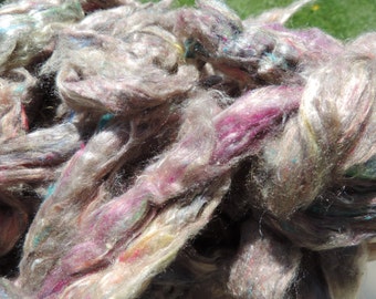 May include: A close-up of a pile of colorful, fluffy fiber. The fiber is a mix of white, gray, pink, and blue. It is perfect for spinning or felting.