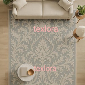 May include: An overhead view of a living room rug with a light blue background and a large, ornate, beige floral pattern. The rug is rectangular and sits beneath a beige sofa, a round coffee table, and two side tables.