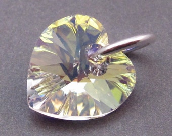 May include: A heart-shaped pendant featuring a faceted, iridescent crystal that reflects light in shades of yellow, green, and blue. The crystal is attached to a polished silver-toned metal jump ring, creating a reflective and geometric appearance.