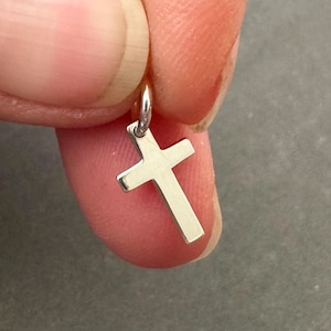 May include: A small silver cross charm pendant.