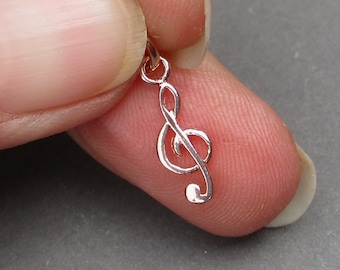May include: A small, rose gold treble clef charm pendant. The charm is detailed and has a smooth finish.