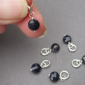 May include: Six silver charms with dark blue gemstone beads. The charms have a loop for attaching to a bracelet or necklace.