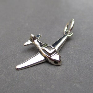 May include: Silver airplane charm with a detailed design. The charm has a loop at the top for attaching to a necklace or bracelet.