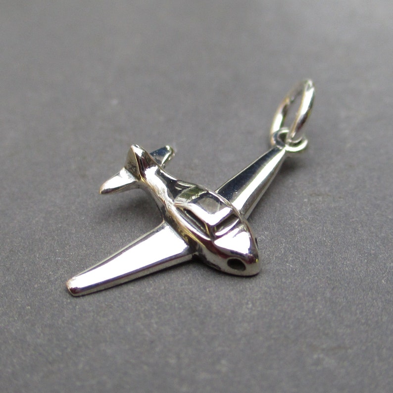May include: Silver airplane charm with a detailed design. The charm has a loop at the top for attaching to a necklace or bracelet.