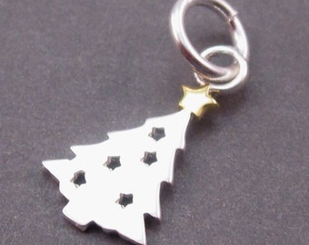 May include: A silver-coloured metal charm shaped like a Christmas tree with cut-out star shapes throughout the body. The tree is topped with a small gold-coloured star and is attached to a circular silver-coloured jump ring for hanging purposes.