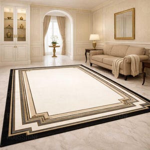 May include: A rectangular rug with a cream central area and a geometric border in black, grey, and beige. The rug is on a marble floor in a living room setting.