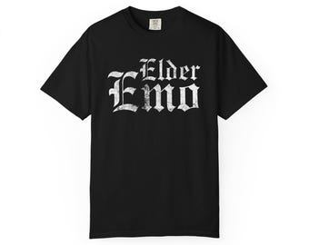 May include: Black t-shirt with the white text "Elder Emo" in a gothic font. The shirt is a short-sleeved crew neck style. The text has a distressed, vintage look.