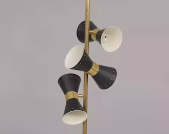 Può includere: Una lampada da terra moderna della metà del secolo con tre paralumi neri a forma di cono. I paralumi hanno un interno bianco e sono accentuati da fasce color oro. La lampada è sostenuta da un palo color oro.