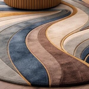 May include: A round area rug with a flowing, wave-like design. The rug features a palette of neutral colors, including beige, gray, brown, and blue, with gold accents. The rug's design creates a sense of movement and adds a touch of elegance to any room.