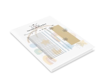 Könnte beinhalten: Ein weißes Notizbuch mit dem Titel "Daily Newborn Tracker" mit floralem Design und pastellfarbenen Aquarellakzenten. Das Notizbuch enthält eine Tabelle zur Verfolgung von Fütterung, Schlaf und Windelwechsel. Das Design umfasst ein hellbraunes Rechteck mit floralem Muster.