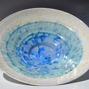 May include: A white ceramic bowl with a blue and green glaze. The bowl has a rippled design and a white rim.