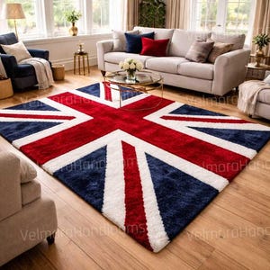 Puede incluir: Una alfombra rectangular con el diseño de la bandera del Reino Unido, con una cruz roja, rayas diagonales blancas y secciones azules. La alfombra está colocada sobre un suelo de madera en un salón.