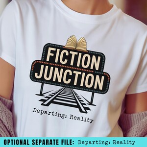 May include: White t-shirt featuring a graphic with the words "FICTION JUNCTION" above a railroad track design. An open book sits atop the sign. The text "Departing: Reality" is below the graphic.