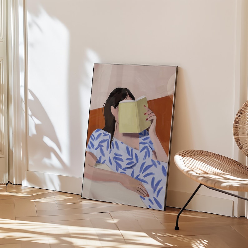May include: An art print featuring a person reading a book, with the book obscuring their face. The person is wearing a blue and white patterned dress. The background has a neutral color palette with a brown accent.