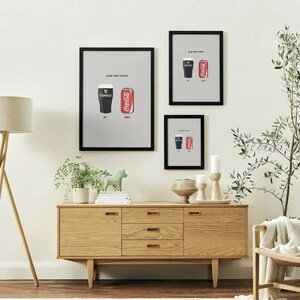Puede incluir: Tres impresiones enmarcadas con marcos negros cuelgan de una pared blanca. Cada impresi&oacute;n presenta un vaso de Guinness y una lata de Coca-Cola. Las impresiones est&aacute;n sobre un mueble de madera. Una l&aacute;mpara de pie tambi&eacute;n es visible.