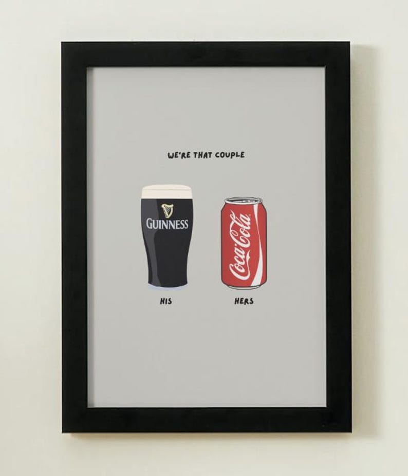 Puede incluir: Impresi&oacute;n enmarcada con una pinta de Guinness y una lata de Coca-Cola, etiquetadas como "His" y "Hers". El texto "WE'RE THAT COUPLE" est&aacute; encima de las bebidas. La imagen tiene un fondo gris.