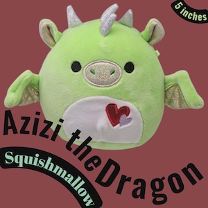 May include: A green plush dragon toy named Azizi the Dragon, approximately 13 cm in size. The dragon has silver horns and ear accents, black eyes, and a white belly with a heart design. The wings have gold accents.