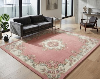 May include: A rectangular area rug featuring a dusty pink base with a central cream-colored floral medallion and a matching ornate border. The design includes intricate scrolling leaf and flower patterns in muted shades of sage green and soft pink.