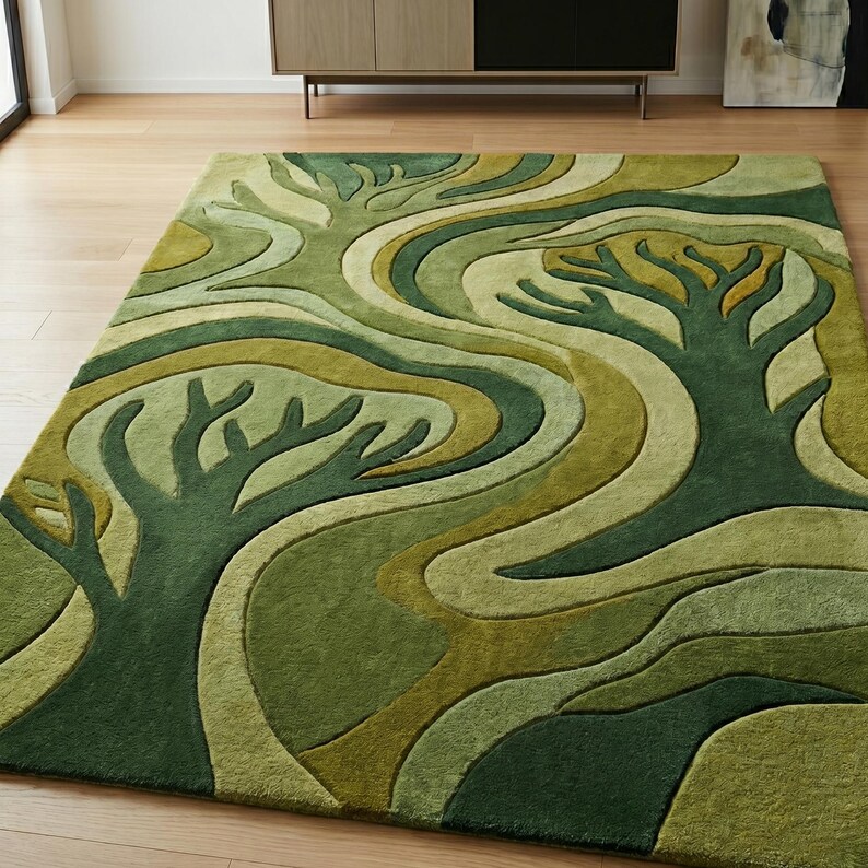 May include: A rectangular area rug with a nature-inspired design. The rug features a pattern of stylized trees and flowing lines in shades of green and olive. The rug is placed on a wooden floor.