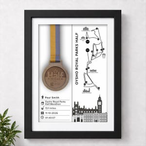 Op de afbeelding: Een ingelijste display met een bronzen Oysho Royal Parks Half finisher-medaille met een blauw en geel lint, een kaart van de 21,08 km lange route en gepersonaliseerde tekst met de naam Paul Smith, datum 11-10-2026 en tijd 01:43:07.