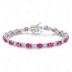 Può includere: Un bracciale color argento caratterizzato da un motivo ripetuto di pietre ovali rosa acceso alternate a piccole pietre rotonde trasparenti. Il gioiello presenta una chiusura a cassetta in metallo sicura con l'incisione S925 sul metallo.